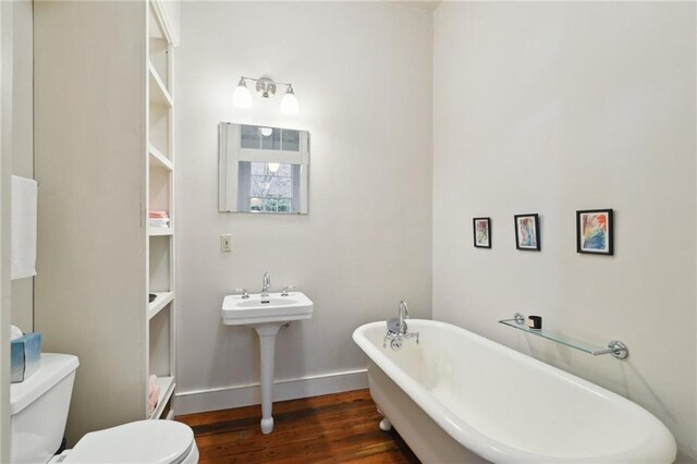 bathroom featuring a bathtub, toilet, and hardwood / wood-style flooring