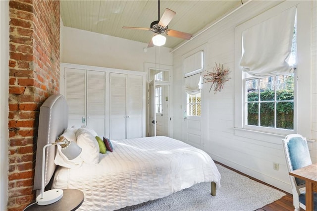 bedroom featuring hardwood / wood-style flooring, ceiling fan, wooden ceiling, and two closets