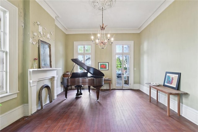 living area with dark wood-type flooring, ornamental molding, and a chandelier