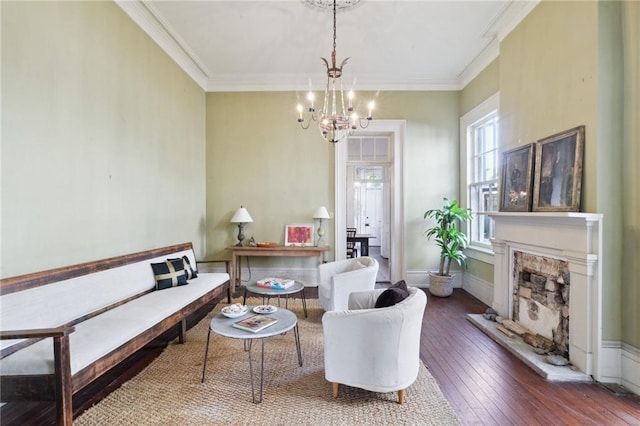 living room featuring an inviting chandelier, crown molding, hardwood / wood-style floors, and a fireplace