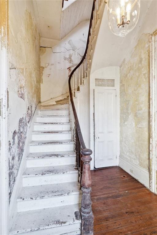 staircase featuring hardwood / wood-style flooring and an inviting chandelier