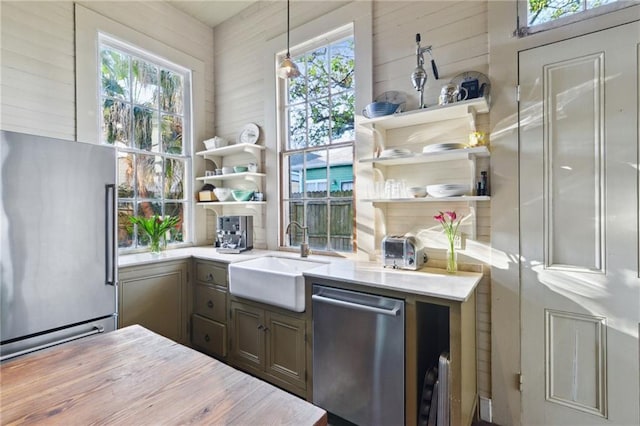 kitchen with appliances with stainless steel finishes, sink, plenty of natural light, and decorative light fixtures