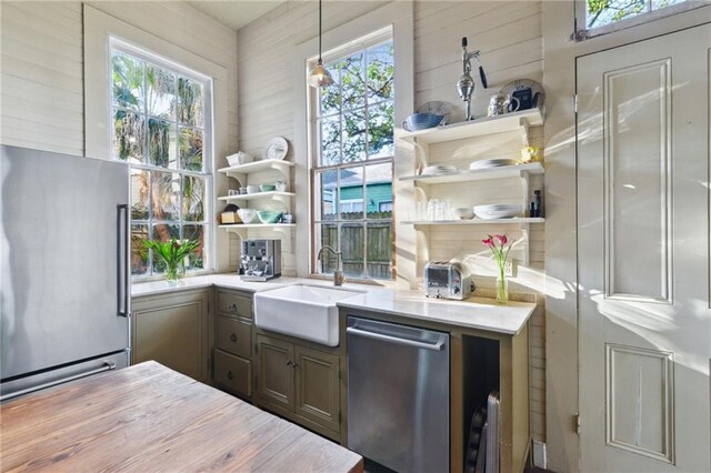 172224 Delachaise St, New Orleans, LA 70115 - kitchen with appliances with stainless steel finishes, a sink, open shelves, light countertops, and wooden walls
