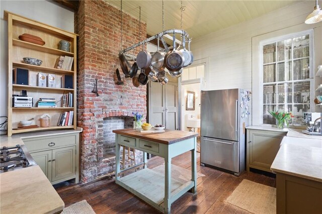 kitchen featuring sink, stainless steel refrigerator, dark hardwood / wood-style flooring, decorative light fixtures, and cooktop