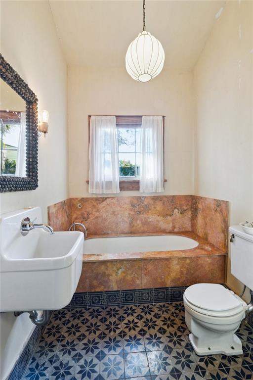 bathroom with lofted ceiling, a healthy amount of sunlight, sink, and toilet