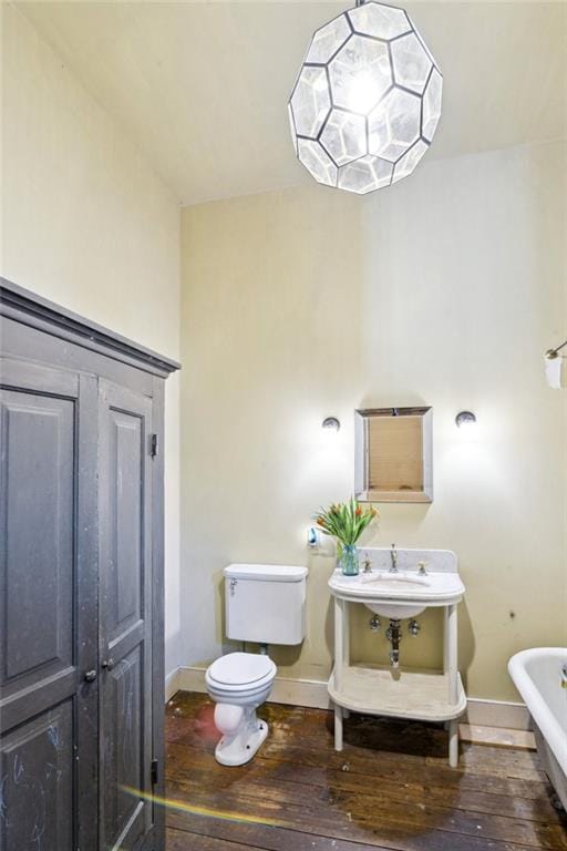 bathroom featuring a tub to relax in, wood-type flooring, and toilet