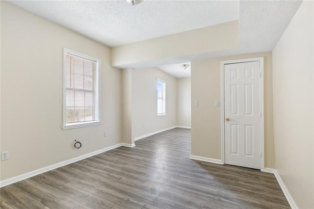 empty room with dark hardwood / wood-style flooring and a textured ceiling