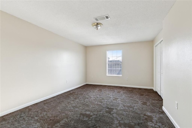 carpeted empty room featuring a textured ceiling