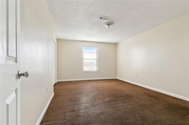 empty room featuring a textured ceiling and dark colored carpet