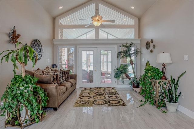 living room with high vaulted ceiling, french doors, ceiling fan, and light wood-type flooring