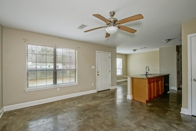 kitchen with ceiling fan, sink, and a center island with sink