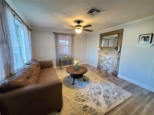 living room featuring wood-type flooring, ornamental molding, ceiling fan, and a textured ceiling