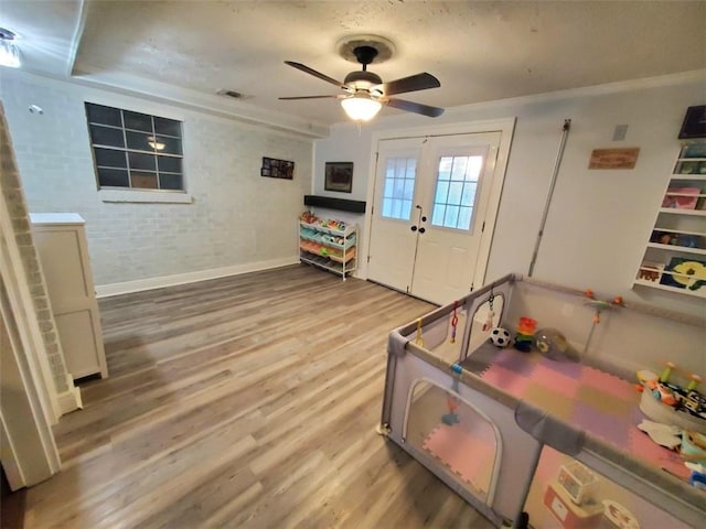 rec room with hardwood / wood-style flooring, brick wall, ceiling fan, and french doors