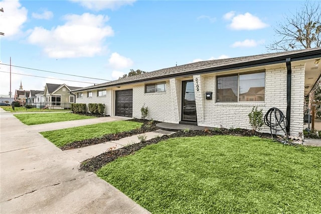 ranch-style house featuring concrete driveway, brick siding, a garage, and a front lawn