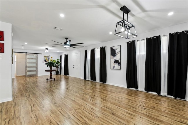 interior space featuring light hardwood / wood-style floors, a barn door, and ceiling fan