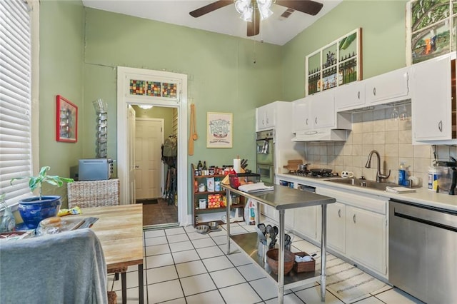 kitchen featuring sink, white cabinetry, light tile patterned floors, dishwasher, and decorative backsplash