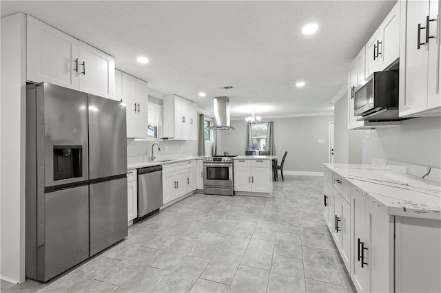 kitchen with white cabinetry, appliances with stainless steel finishes, kitchen peninsula, island exhaust hood, and light stone countertops