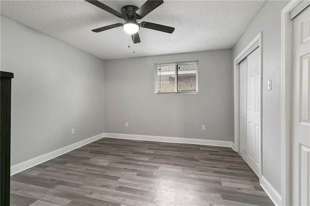 unfurnished bedroom featuring ceiling fan, a closet, dark hardwood / wood-style flooring, and a textured ceiling