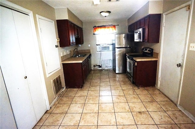 kitchen with stainless steel appliances, sink, and light tile patterned floors