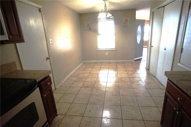 unfurnished dining area featuring an inviting chandelier, a textured ceiling, and light tile patterned flooring