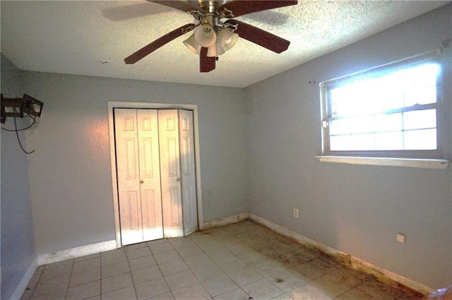 unfurnished bedroom featuring light tile patterned floors, a closet, a textured ceiling, and ceiling fan