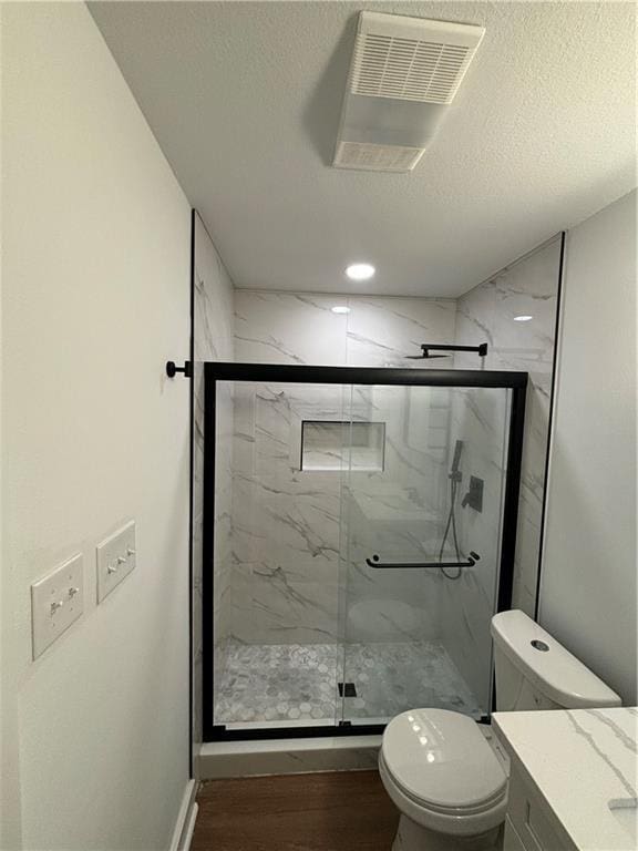 bathroom featuring walk in shower, toilet, wood-type flooring, a textured ceiling, and vanity