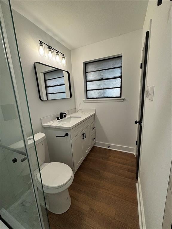 bathroom with vanity, toilet, a shower with door, and hardwood / wood-style floors