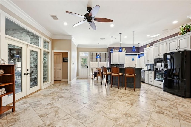 kitchen with black appliances, french doors, white cabinets, and a kitchen bar