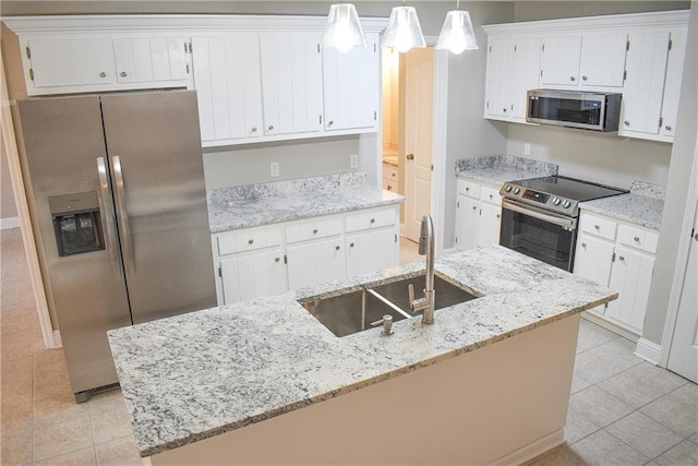 kitchen featuring light tile patterned flooring, decorative light fixtures, sink, a kitchen island with sink, and stainless steel appliances