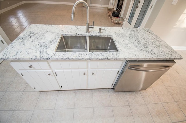 kitchen featuring light tile patterned floors, dishwasher, sink, and white cabinets