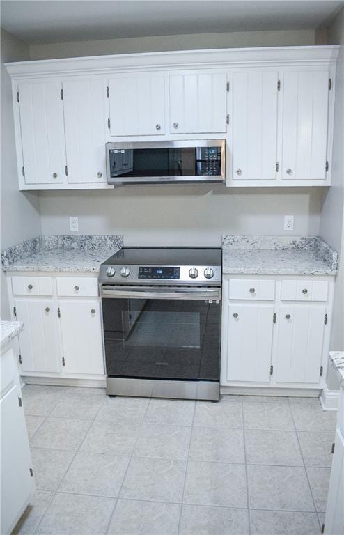 kitchen with light stone countertops, appliances with stainless steel finishes, and white cabinets