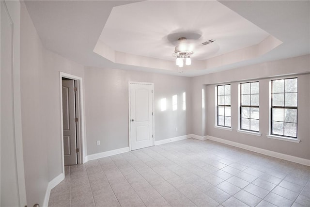 unfurnished room with light tile patterned flooring and a tray ceiling