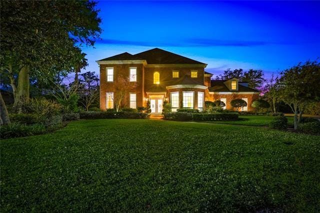 back house at dusk featuring a yard and french doors