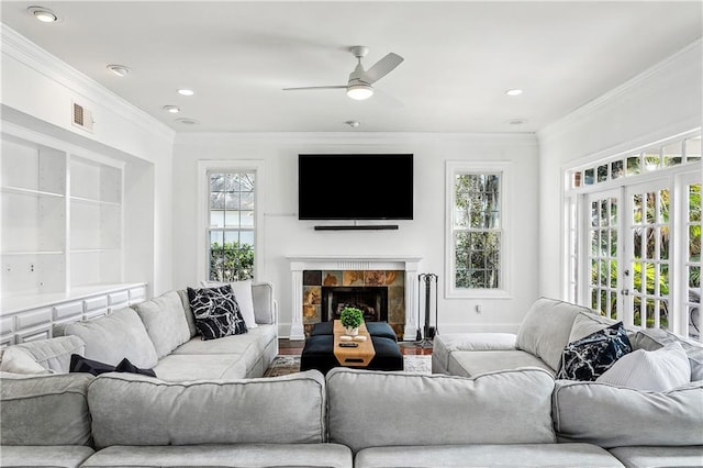 living room with ornamental molding, ceiling fan, a fireplace, and french doors