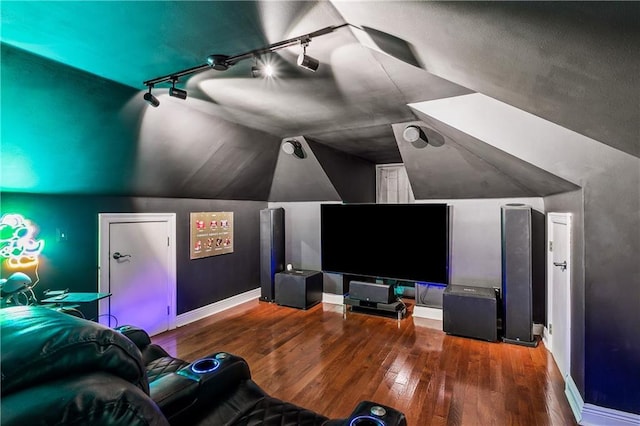 home theater room featuring hardwood / wood-style flooring, rail lighting, and vaulted ceiling