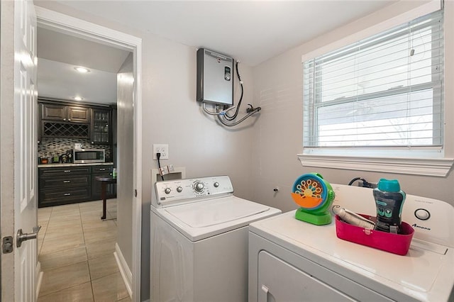 laundry room featuring washer and clothes dryer, water heater, and light tile patterned floors