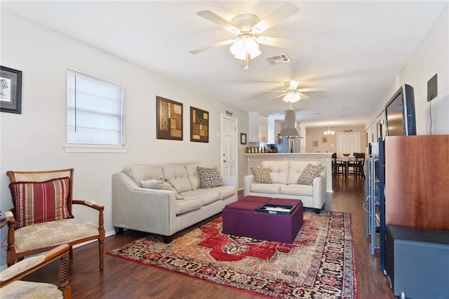 living room with dark hardwood / wood-style flooring and ceiling fan with notable chandelier