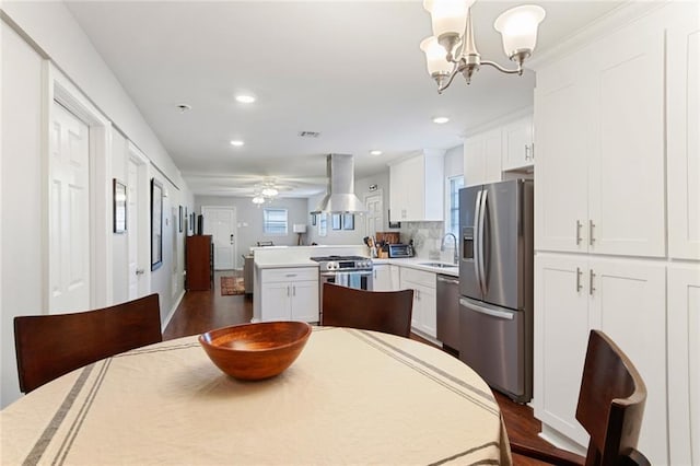 kitchen featuring pendant lighting, sink, appliances with stainless steel finishes, white cabinets, and island exhaust hood