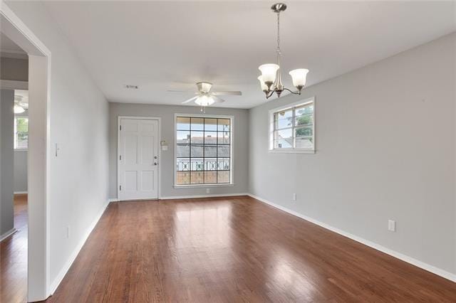 spare room with dark hardwood / wood-style flooring and ceiling fan with notable chandelier