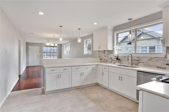 kitchen featuring hanging light fixtures, sink, white cabinets, and kitchen peninsula