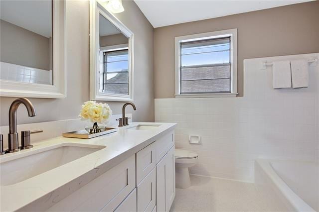 bathroom featuring toilet, tile walls, vanity, a bathing tub, and tile patterned flooring