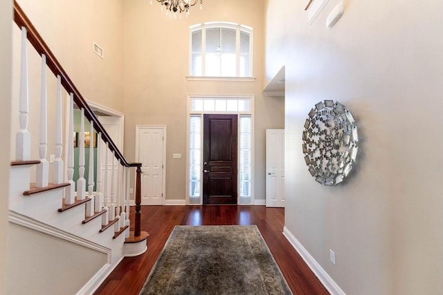 entryway featuring a towering ceiling and dark wood-type flooring