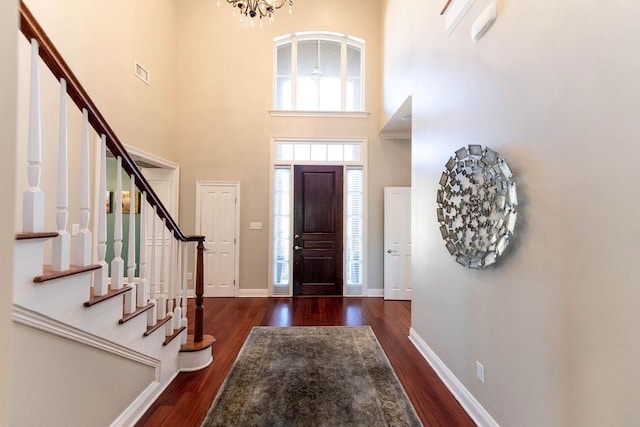 entrance foyer featuring stairs, wood finished floors, baseboards, visible vents, and an inviting chandelier