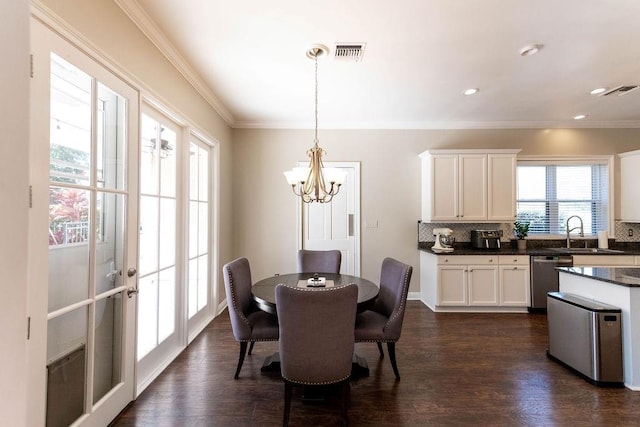 dining space featuring crown molding, sink, dark wood-type flooring, and a notable chandelier