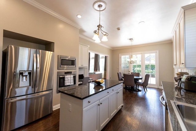 kitchen featuring appliances with stainless steel finishes, pendant lighting, white cabinets, and dark stone counters