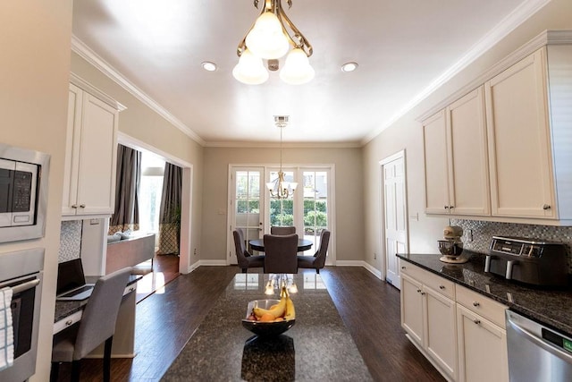 kitchen with decorative light fixtures, white cabinetry, dark stone countertops, a notable chandelier, and stainless steel appliances