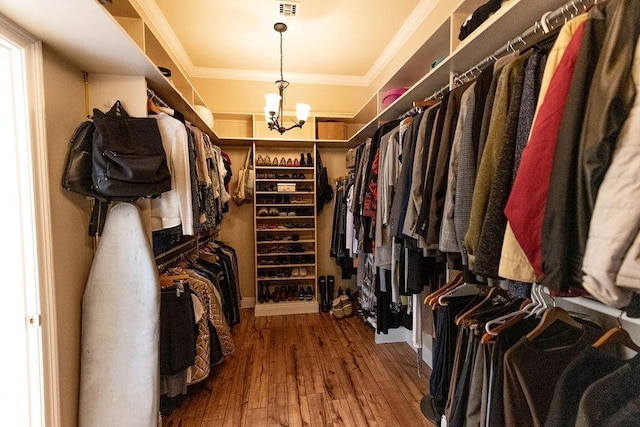 walk in closet with wood-type flooring and a chandelier