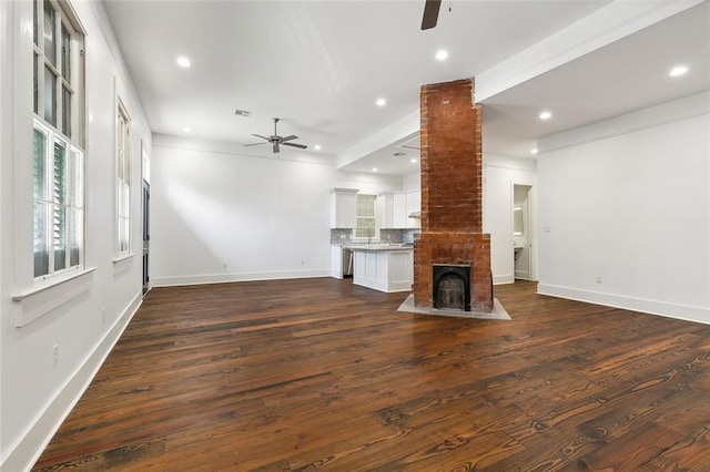 unfurnished living room featuring dark wood-type flooring, ceiling fan, and a fireplace