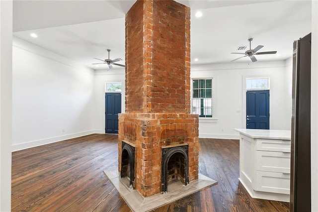 unfurnished living room featuring a brick fireplace, dark wood-type flooring, and ceiling fan