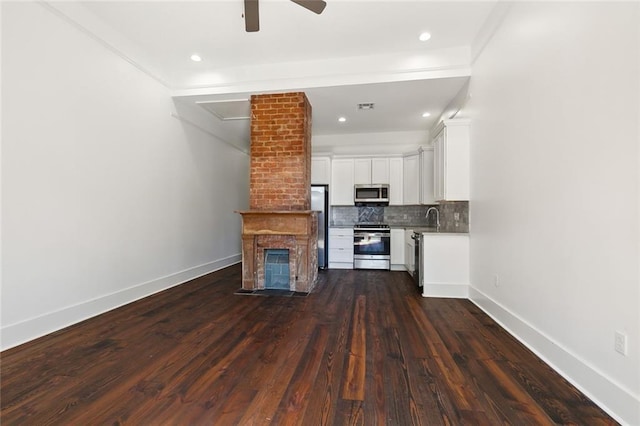 unfurnished living room featuring dark hardwood / wood-style flooring, sink, a brick fireplace, and ceiling fan